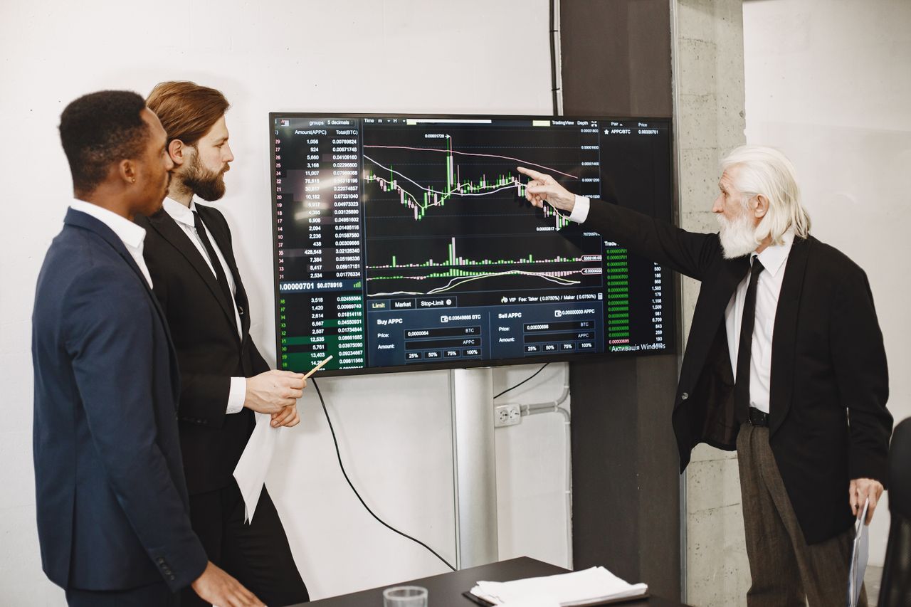 services-02 A diverse business team in a meeting analyzing stock market data on a screen.
